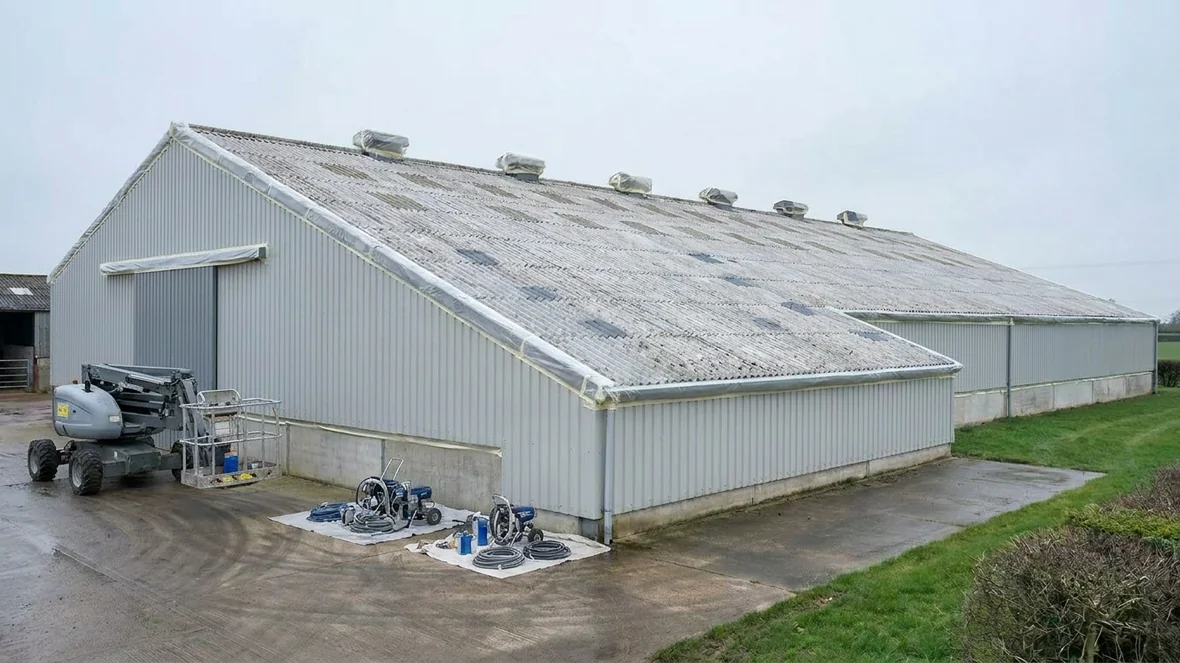 Masked ridge vents and primed repairs before roof coating on a grain store near Taunton