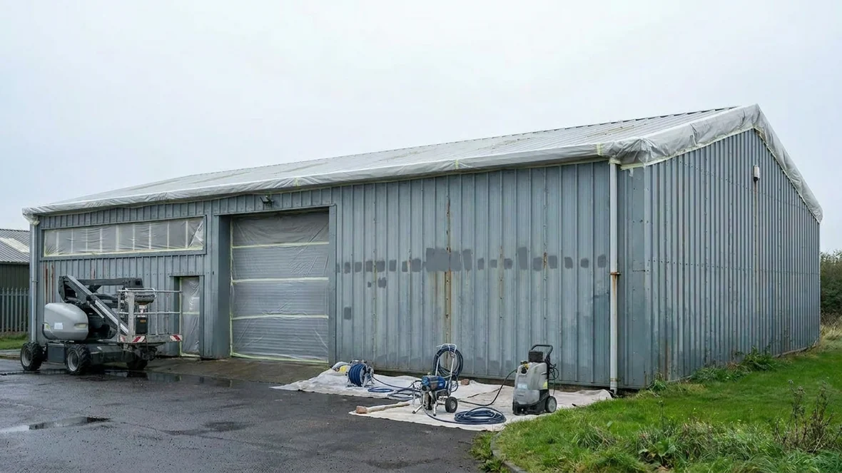 Masked windows and doors before cladding spraying on an industrial unit near Warrington