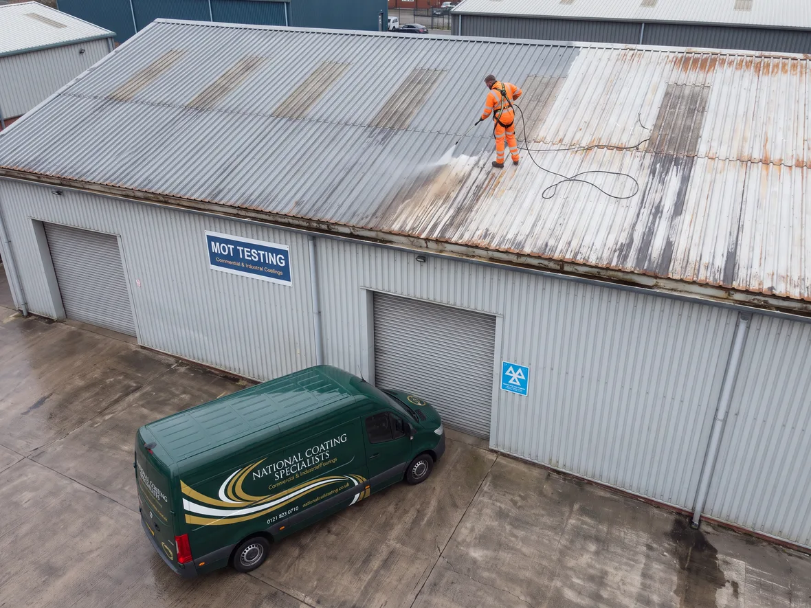 Pressure washing during roof coating on an MOT garage near Swindon