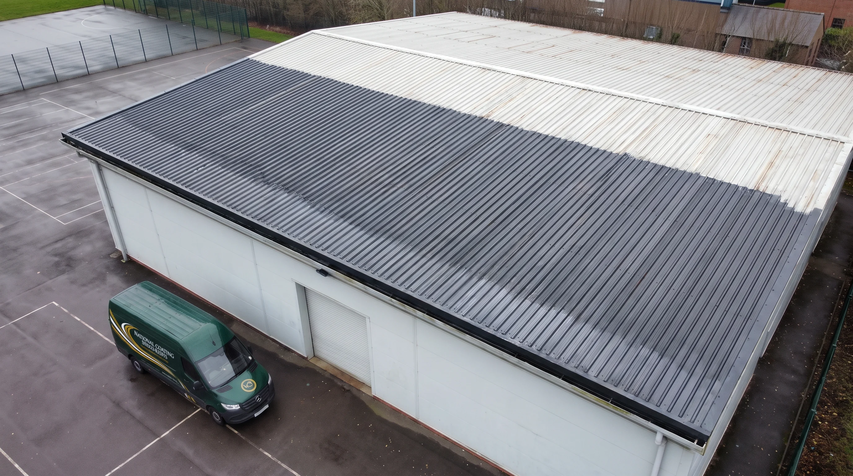 Spraying anthracite roof coating on school sports hall near Reading