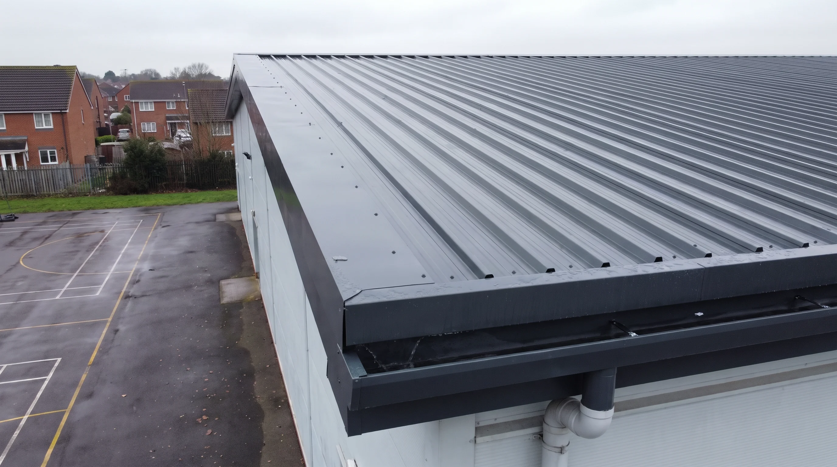 Coated roof edge detail at the gutter on school sports hall near Reading
