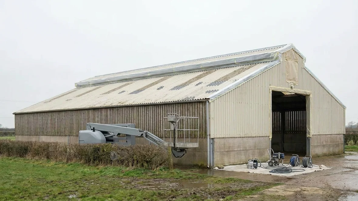 Masking rooflights and edges during roof coating on a sheep shed near Wakefield
