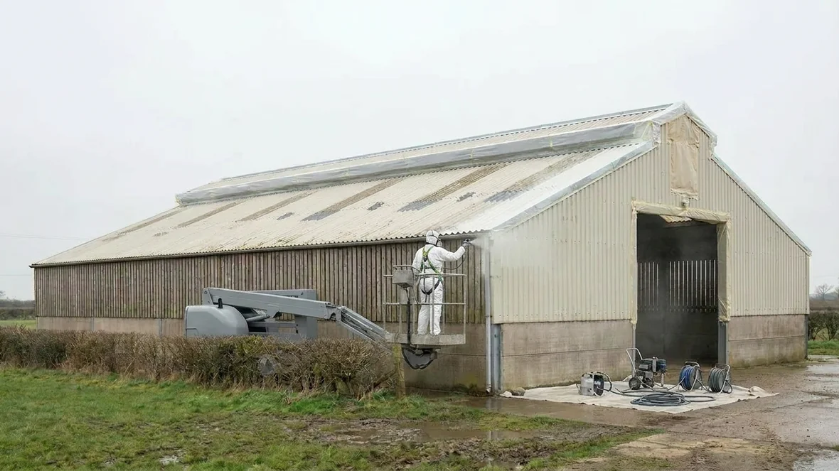 Airless spraying the roof from a MEWP during roof coating on a sheep shed near Wakefield
