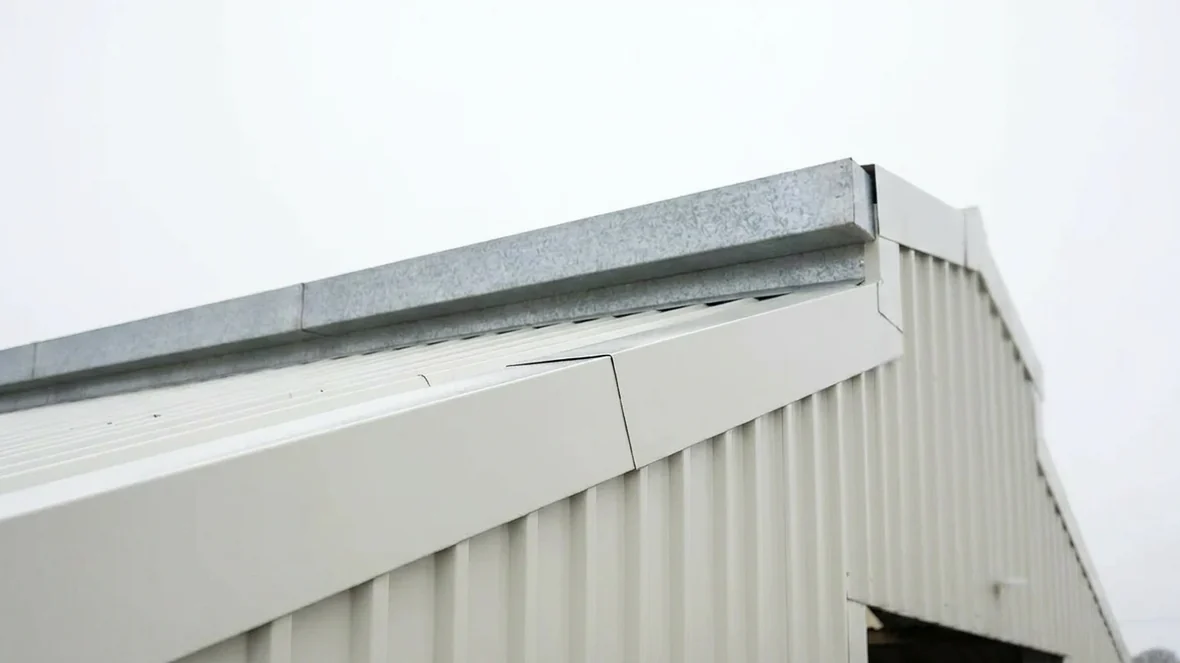 Primed cut edges and fixings during roof coating on a sheep shed near Wakefield