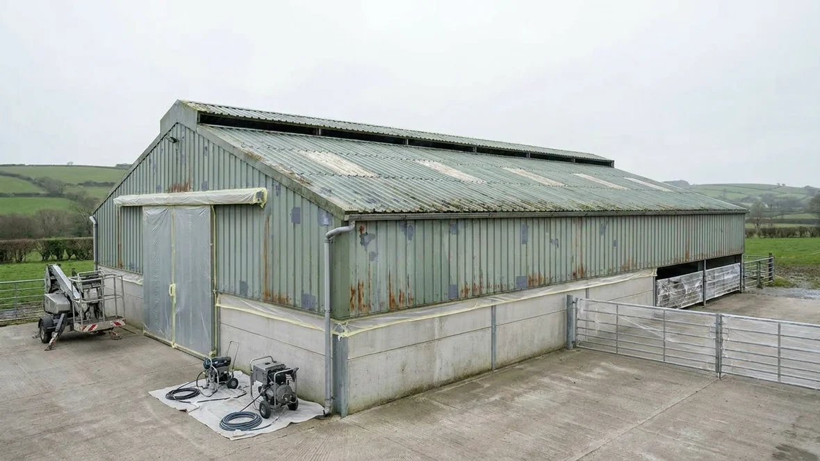 Masked doors and primed repairs before coating on a dairy unit near Carmarthen