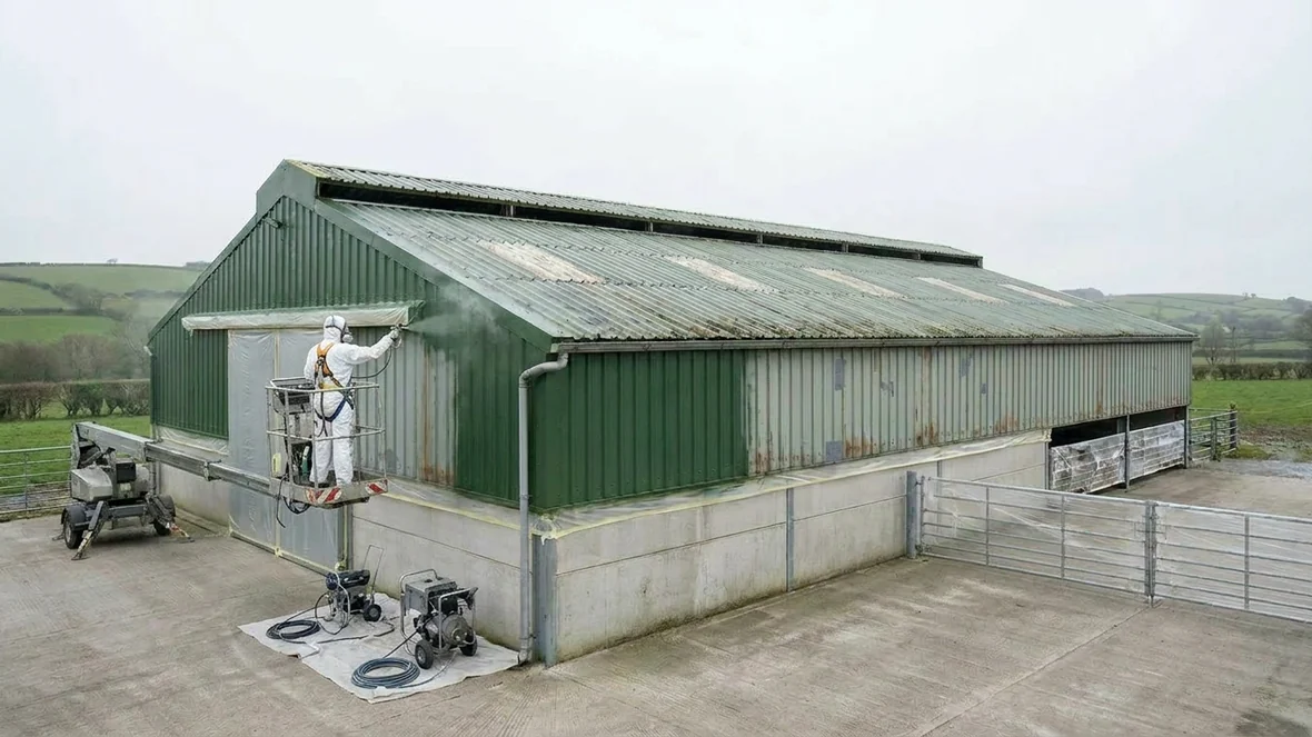 Airless spraying moorland green coating on dairy unit cladding near Carmarthen