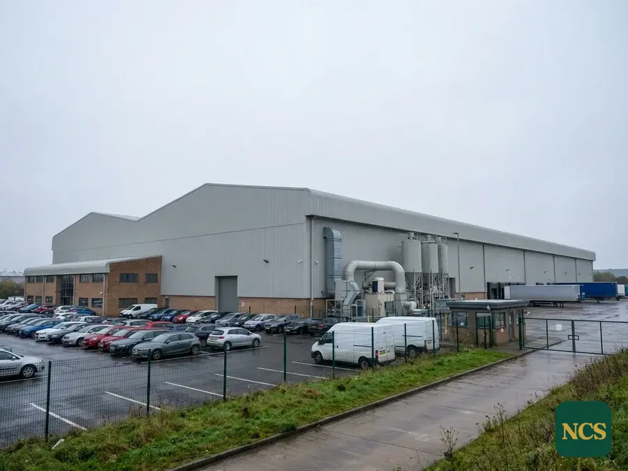 A freshly coated grey metal roof across a large manufacturing plant.