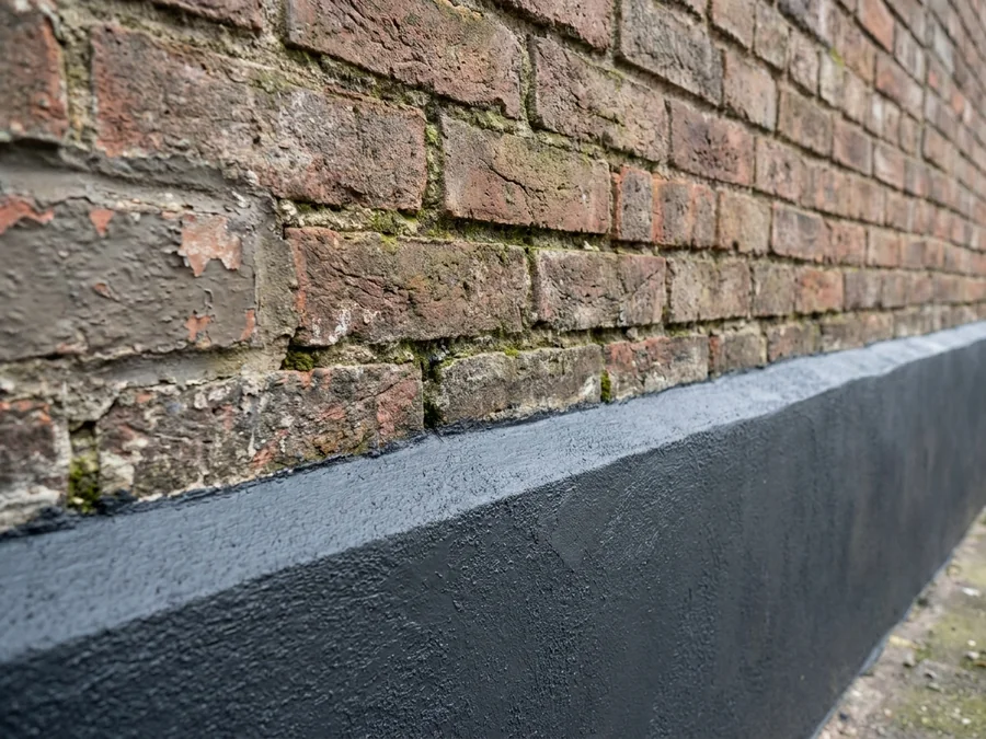 Close-up of failing mortar joints on a brick-built industrial building, a common cause of penetrating damp.
