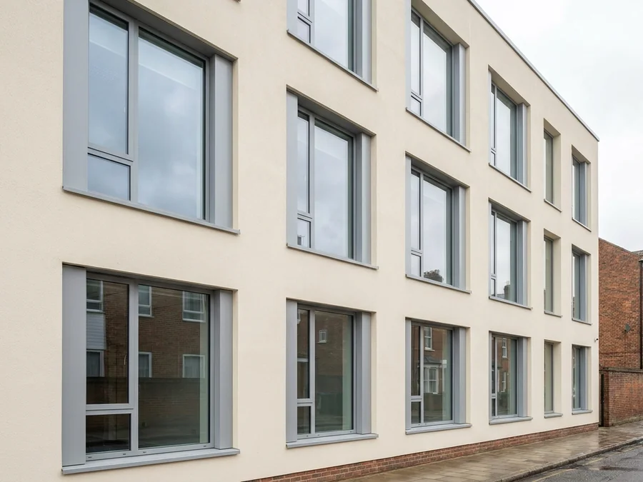 Repairing and coating a cracked rendered wall on a factory unit.