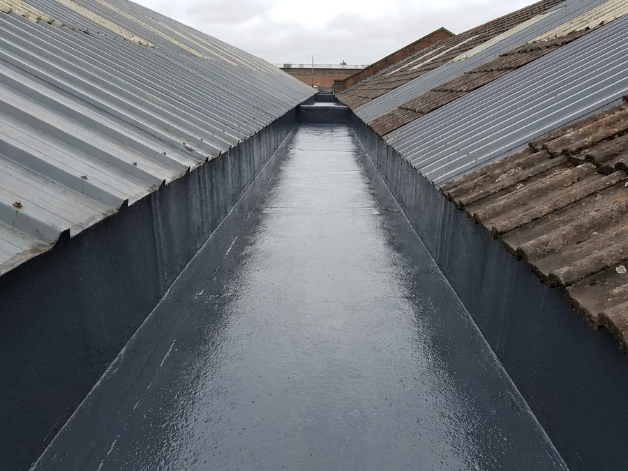Lining being installed in a metal valley gutter on an industrial unit.