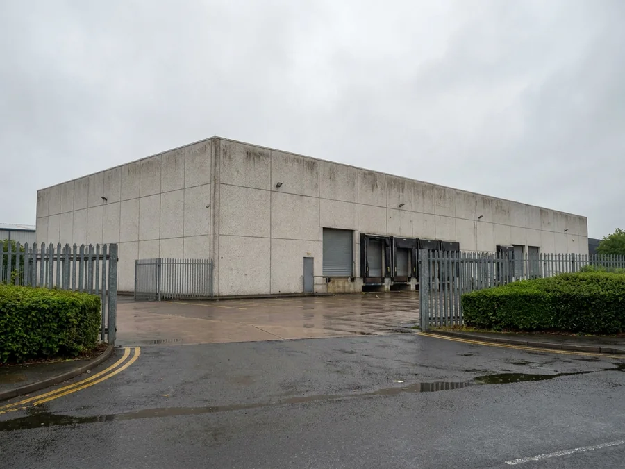 A large warehouse exterior wall after pressure washing and before spray coating application.