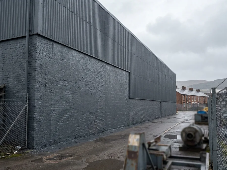 A logistics unit's metal cladding wall half-coated, showing the before and after contrast.