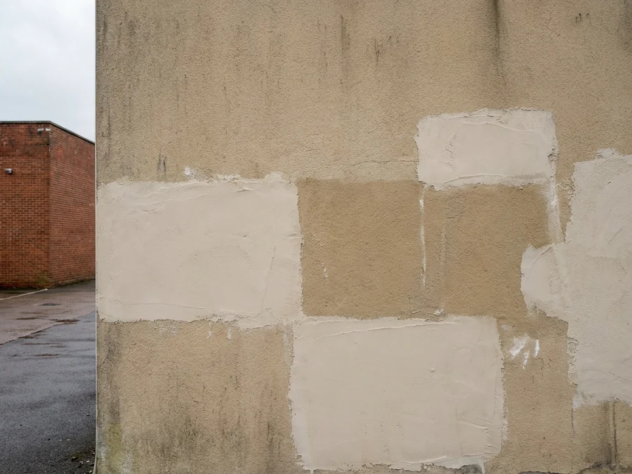 Cracked render on an industrial unit warehouse wall, cut out and repaired before coating.